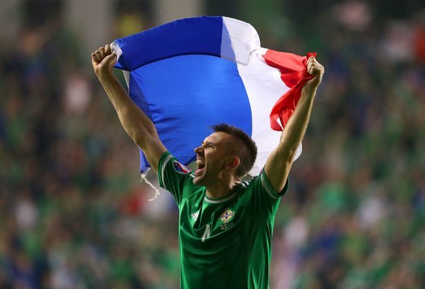 Gareth McAuley da Irlanda do Norte agita uma bandeira francesa após o apito final