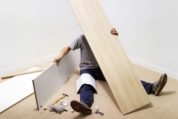 フラットパック家具を組み立てる床に座っている男