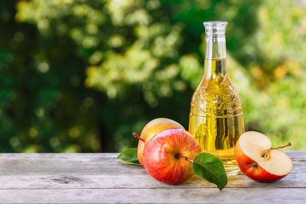 Sidra de poma, suc o vinagre en ampolla de vidre sobre taula de fusta. Beguda d'estiu
