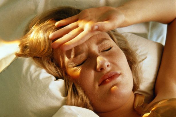 Žena ležiaca v posteli, zavreté oči, ruka na čele, detail