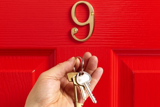 Agente imobiliário e chaves na frente da porta vermelha
