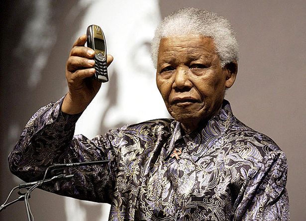 Nelson Mandela brandit un téléphone mobile lors du lancement d'une nouvelle initiative caritative pour lutter contre les problèmes de SIDA/VIH dans le monde au London Hilton