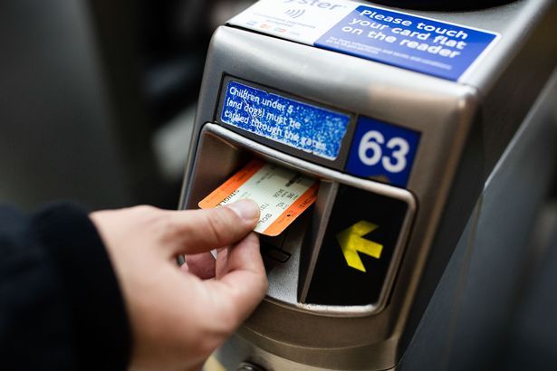 Dochádzajúci kladie papierový lístok cez čítačku na bariéru lístkov na železničnej stanici London Marylebone